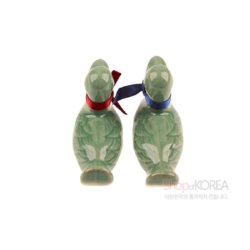연녹색 청자 재질에 원앙 형상을 빚어낸 수저받침 세트, 붉은색과 파란색 리본 장식이 특징인 제품.