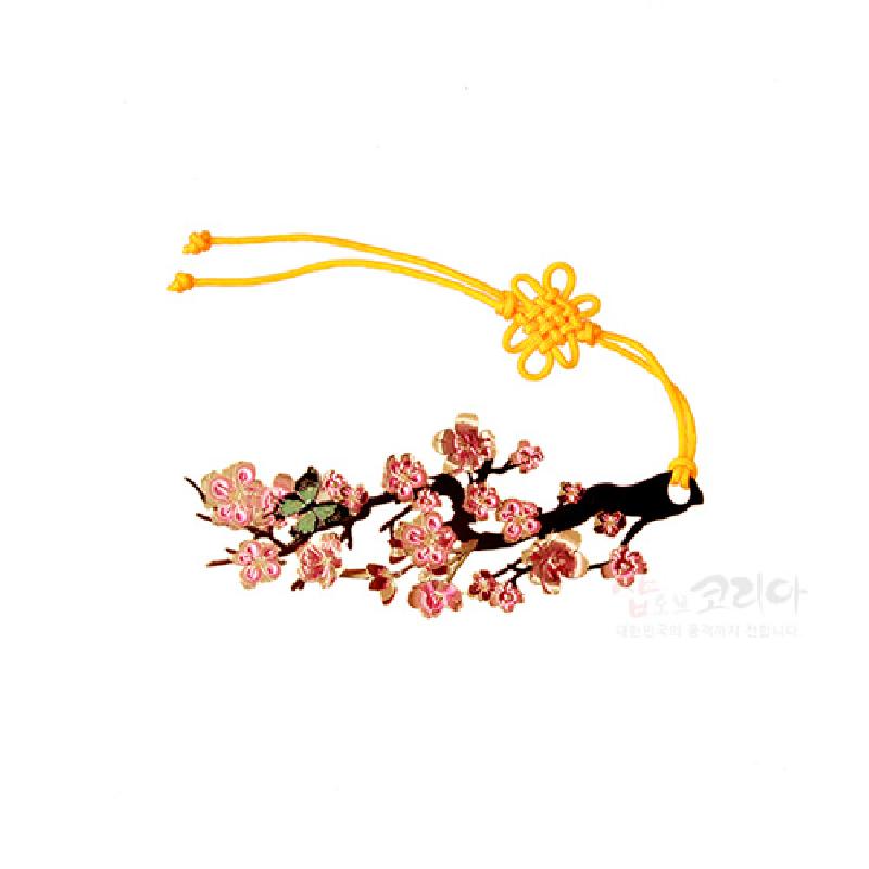 금속 소재에 자개 상감으로 표현된 분홍 매화나무 문양과 노란색 전통 매듭 장식이 어우러진 책갈피.