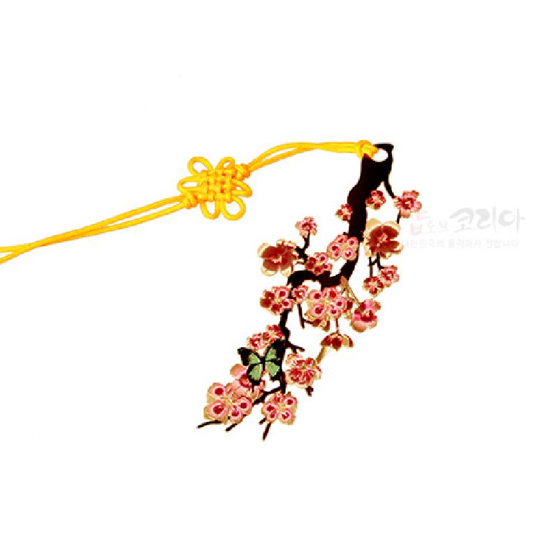 금속 재질에 금장 처리된 매화나무 가지와 분홍 꽃 문양, 노란색 전통 매듭 끈 장식의 책갈피.