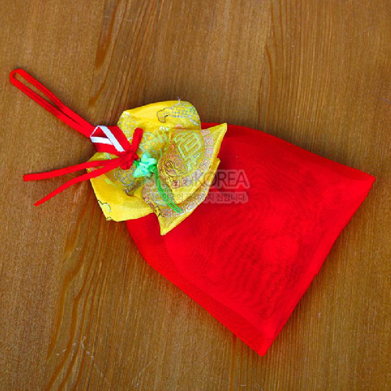 붉은 비단 치마 형태의 주머니와 황색 비단 당의 깃, 금색 전통 문양과 붉은 끈 장식이 조화를 이룬 향주머니. 붉은 비단 치마 형태의 주머니와 황색 비단 당의 깃, 금색 전통 문양과 붉은 끈 장식이 조화를 이룬 향주머니.