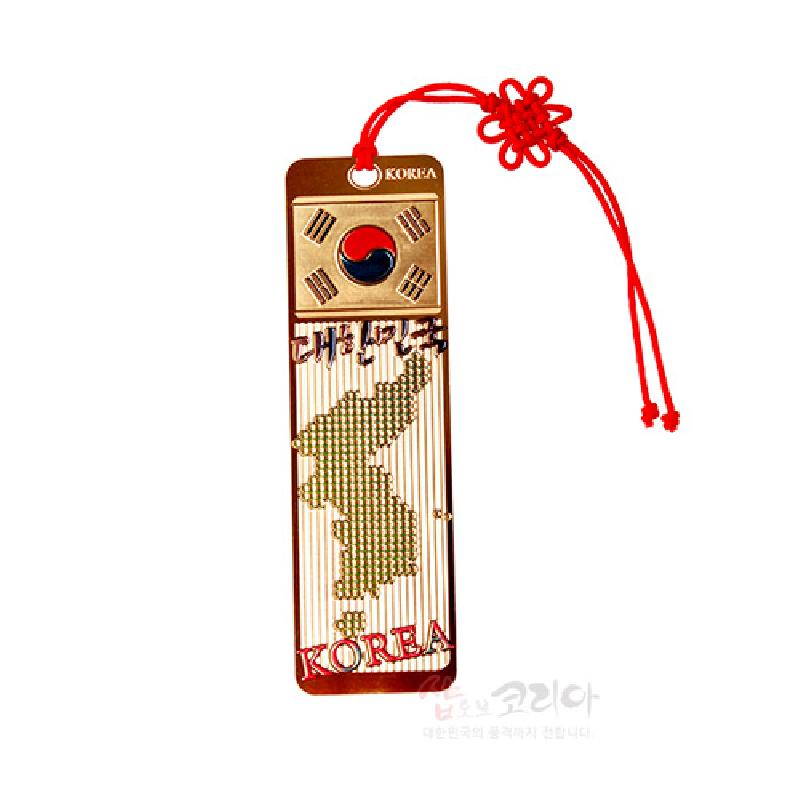 금속 재질에 태극기와 대한민국 지도를 입체적으로 새긴 금장 책갈피, 붉은 전통 매듭 장식 끈이 달린 디자인.