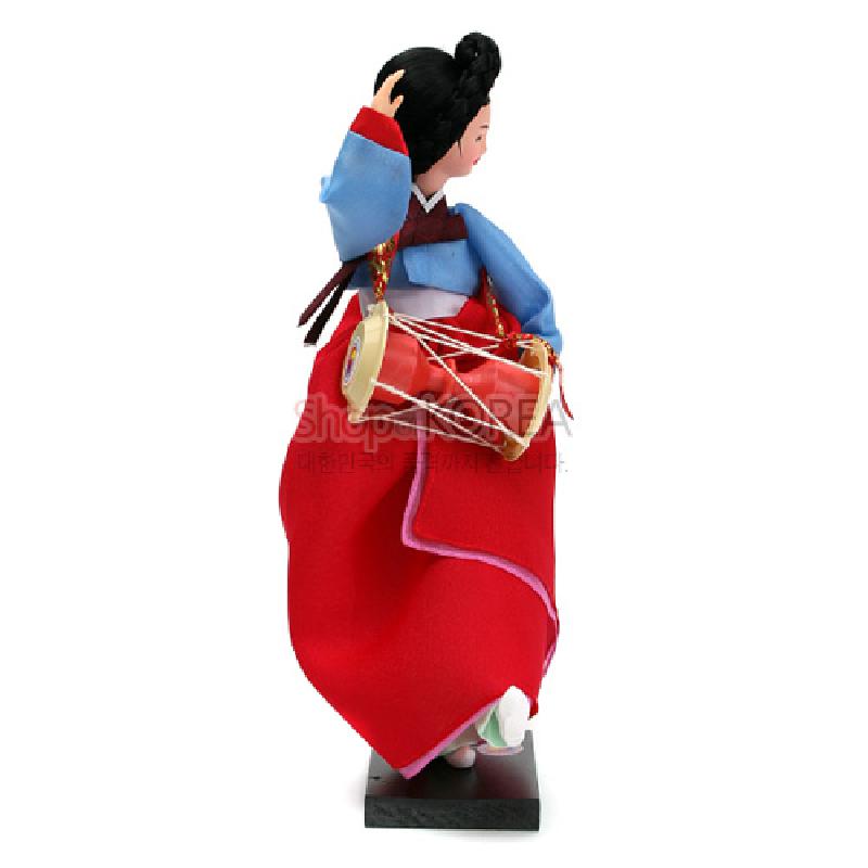 붉은 치마와 하늘색 저고리의 비단 느낌 한복, 장구와 흰 끈 장식이 조화를 이루는 전통 무용수 인형.