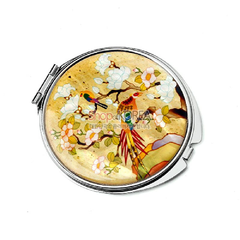 금속 테두리에 자개를 상감해 황색 바탕 위 화조채색 문양과 매화·꽃나무를 섬세하게 표현한 원형 손거울.