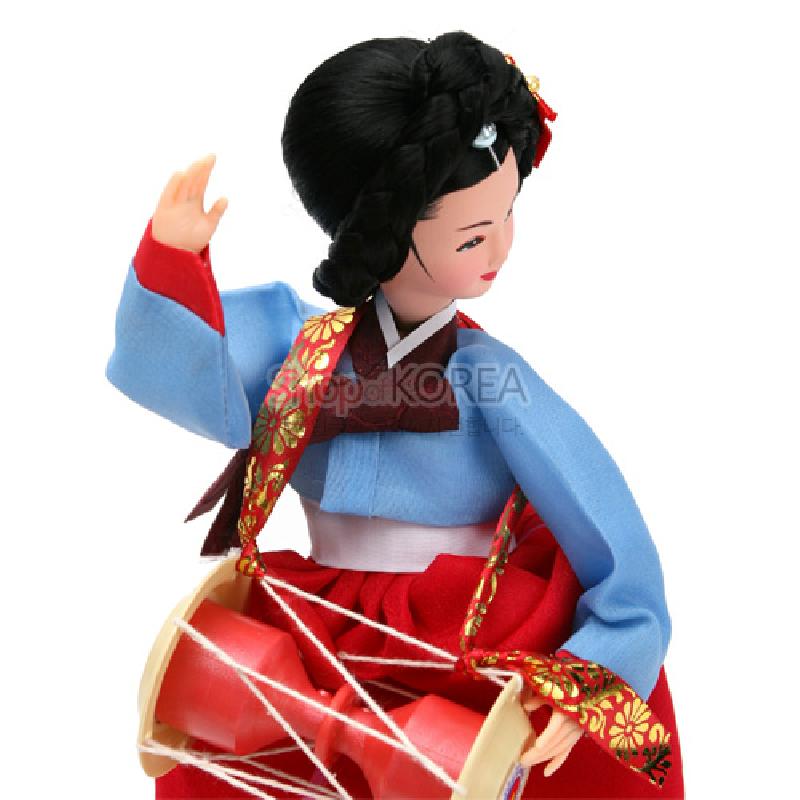 붉은 치마와 하늘색 저고리의 비단 느낌 한복, 금색 꽃무늬 장식 끈과 장구 소품이 조화된 전통 한복 인형.