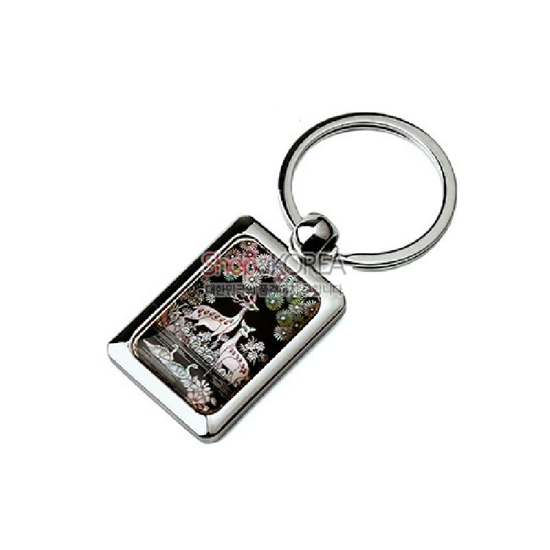 검은 바탕 자개 상감 위에 장생도 사슴과 꽃 문양이 새겨진 금속 테두리 열쇠고리형 장식.