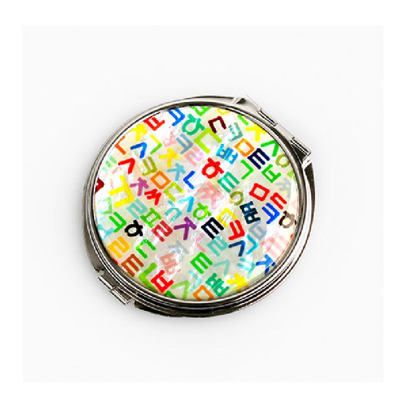 자개 바탕 위에 다채로운 색상의 훈민정음 자모 문양을 배치한 금속 테두리 손거울. 자개 바탕 위에 다채로운 색상의 훈민정음 자모 문양을 배치한 금속 테두리 손거울.