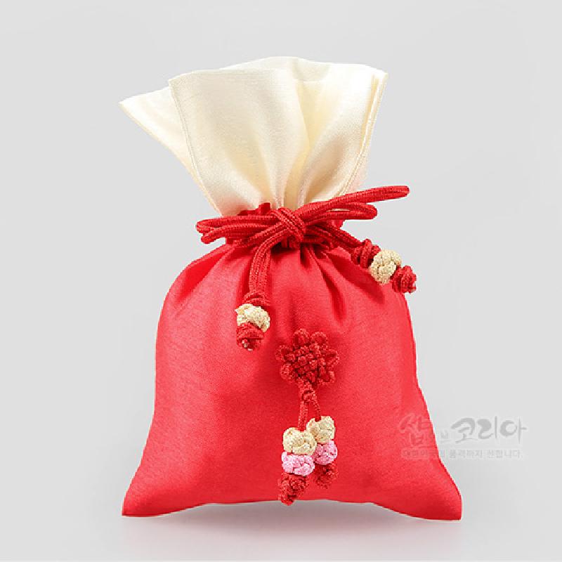 적색 비단 원단에 아이보리색 상단 처리와 홍색 끈 매듭 장식, 꽃 모양 매듭 술이 포인트인 전통 매듭주머니.