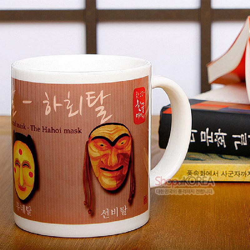 하회탈을 사실적으로 인쇄한 세라믹 재질 머그컵, 갈색 계열 배경과 한글·영문 서체 장식이 특징인 디자인.