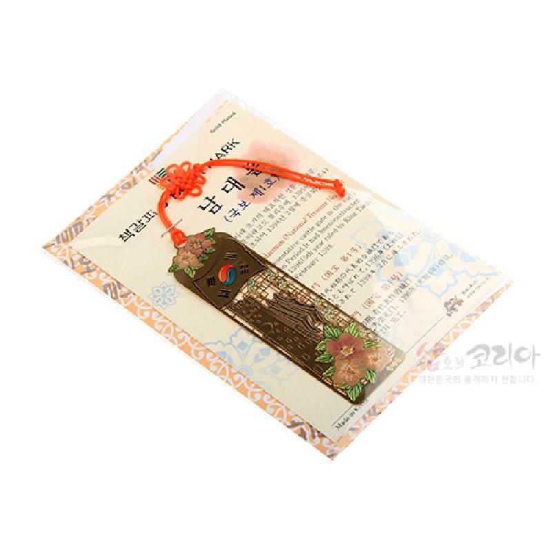 금속 재질에 남대문 형상과 태극 문양, 분홍색 무궁화 꽃문양을 상감한 금장 책갈피, 주황색 전통 매듭끈 장식.
