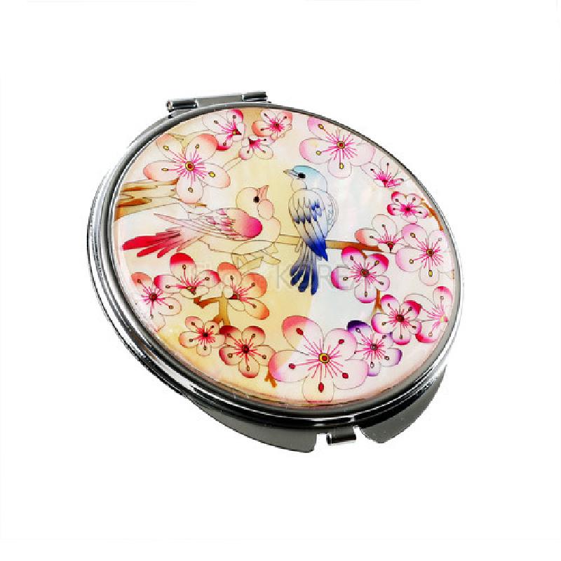 자개를 사용한 원형 손거울로, 자개 바탕 위에 분홍 매화와 청홍색 매조 문양이 섬세한 채색 기법으로 표현되어 있다.