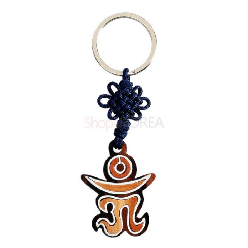 흑단으로 만든 옴 문자 형 열쇠고리로, 나뭇결을 살린 갈색 톤과 흰색 선이 조화되며 청색 전통 매듭이 연결되어 있다.
