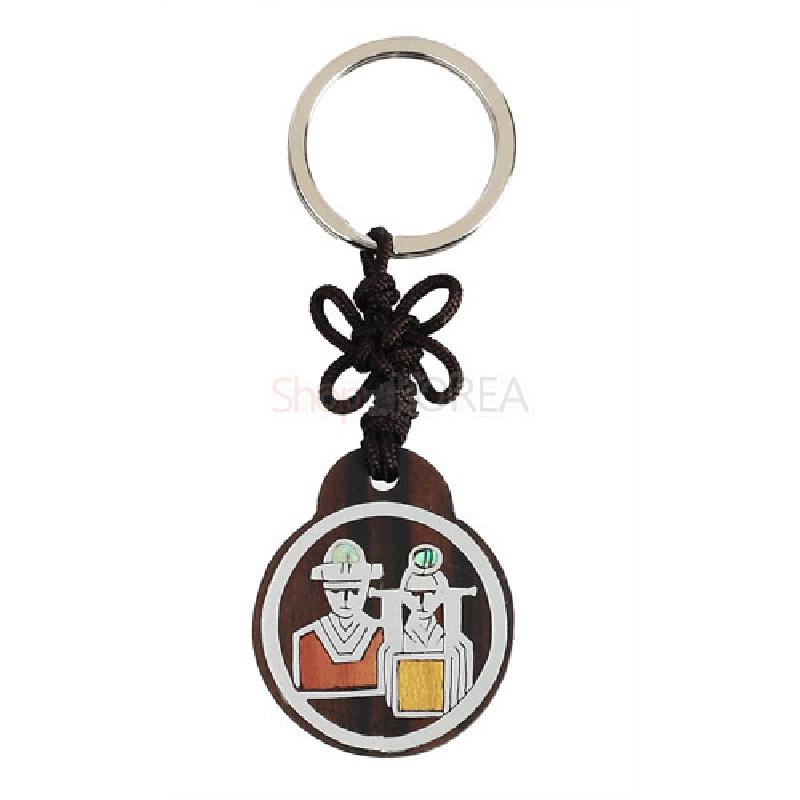 흑단 원형 판에 혼례복 인물을 은색 선으로 새기고 적색·황색 포인트를 넣은 전통 매듭 열쇠고리