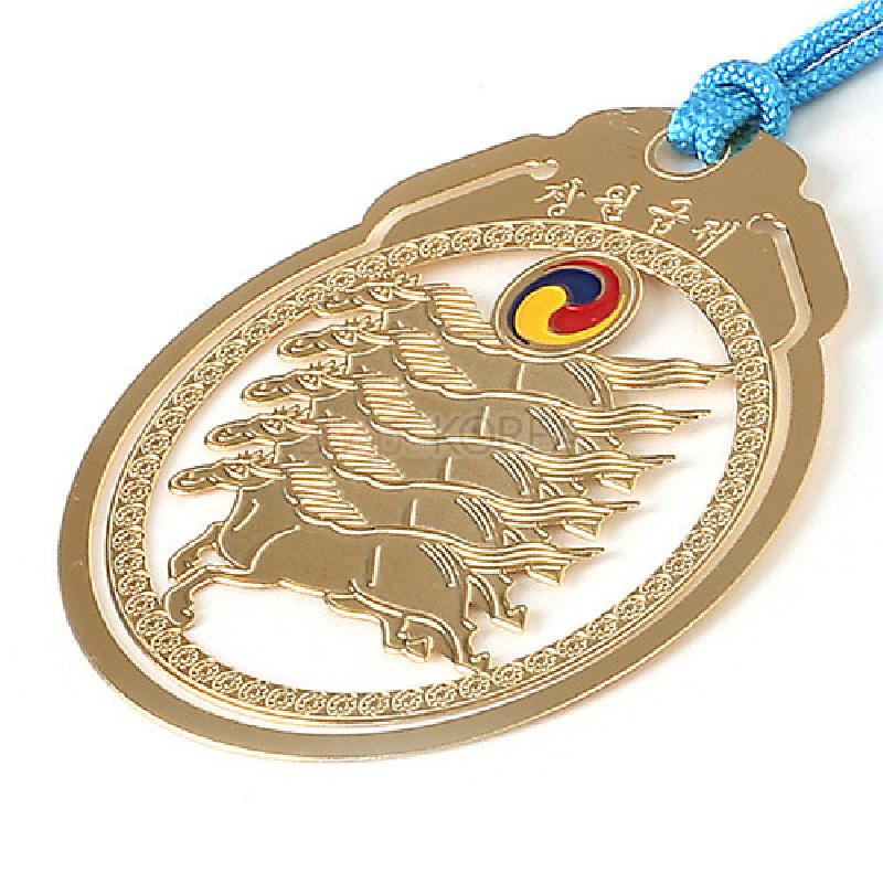 금속 재질로 제작된 마패 형태의 책갈피, 다섯 마리 말 부조와 태극 문양, 푸른 끈 장식이 돋보이는 디자인.