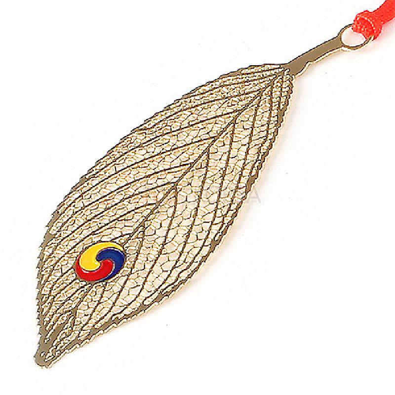 금속 재질의 나뭇잎 형상 책갈피, 섬세한 잎맥 문양과 삼색 태극 문양 장식, 붉은 끈 장식.