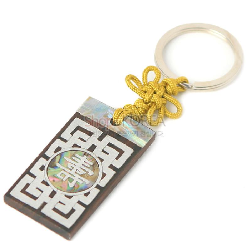 흑단 바탕에 자개 상감으로 수문과 기하학 무늬를 넣은 직사각 열쇠고리, 황금색 전통 매듭 장식 특징 제품.