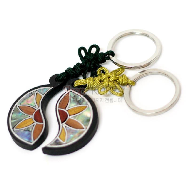 흑단 바탕 위 자개 상감으로 연꽃쌍 문양을 넣고 녹색·황색 전통 매듭과 금속 고리가 연결된 열쇠고리.