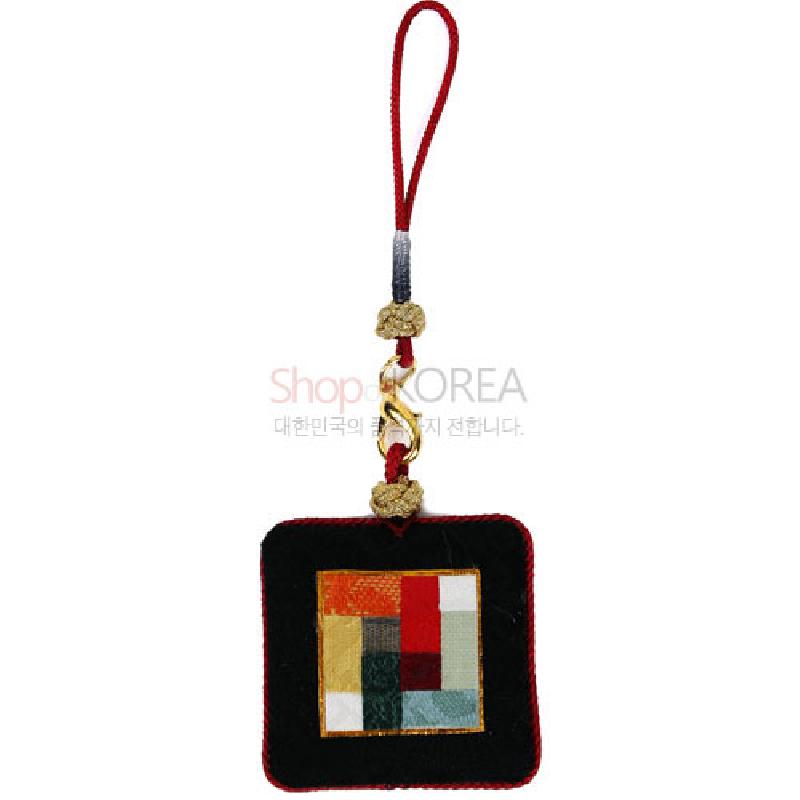 검은 천 바탕에 붉은 테를 두르고, 중앙에 다색 조각보 누비 문양을 넣은 금속 고리 장식 열쇠고리.