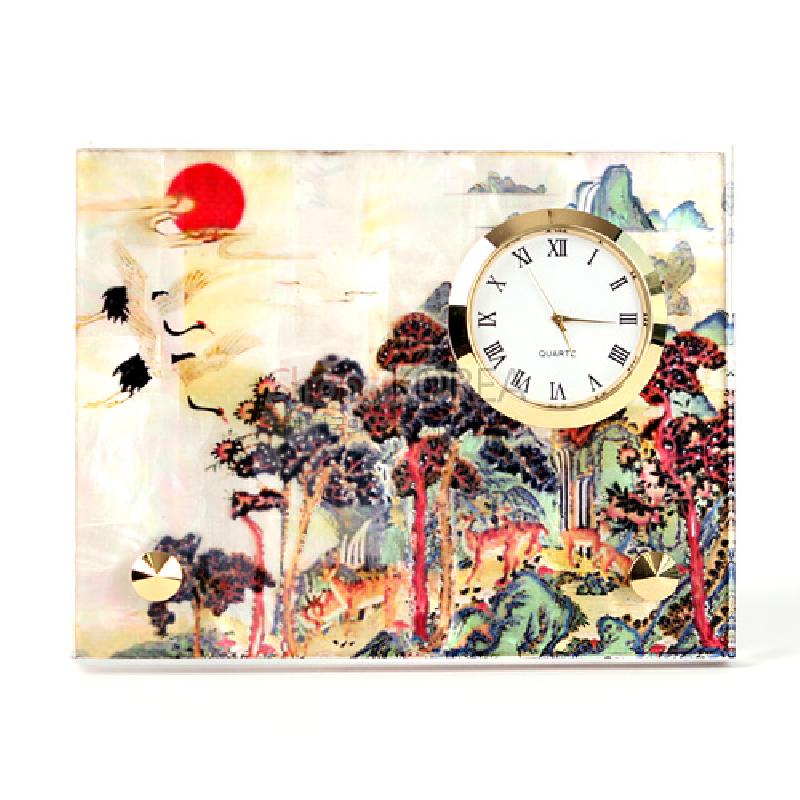 자개 바탕 위에 옻칠된 십장생 민화 산수·학·사슴 문양과 금색 금속 테두리 시계가 조화를 이룬 탁상용 시계.