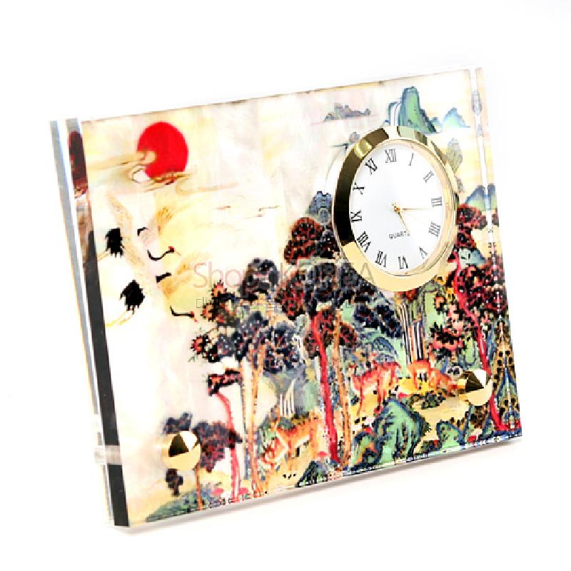 자개 느낌의 광택 있는 판에 십장생 민화풍 산수와 학, 해를 채색한 배경과 금속 테두리 원형 시계가 결합된 탁상용 시계. 자개 느낌의 광택 있는 판에 십장생 민화풍 산수와 학, 해를 채색한 배경과 금속 테두리 원형 시계가 결합된 탁상용 시계.