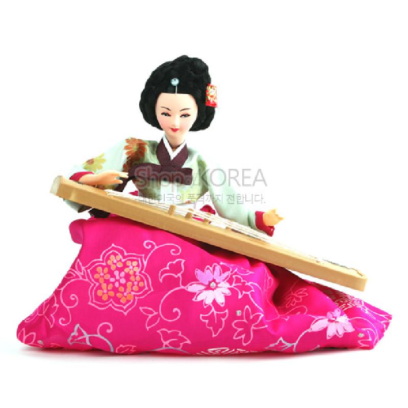 분홍색 비단 치마에 꽃무늬 문양을 더하고 연두색 저고리와 가야금을 표현한 한복 인형 장식.