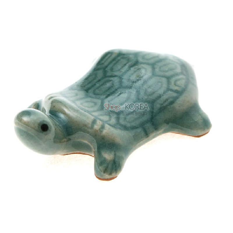 청자 재질에 비취색 유약을 입힌 거북 모양 수저받침, 등껍질 육각 문양이 특징인 디자인.