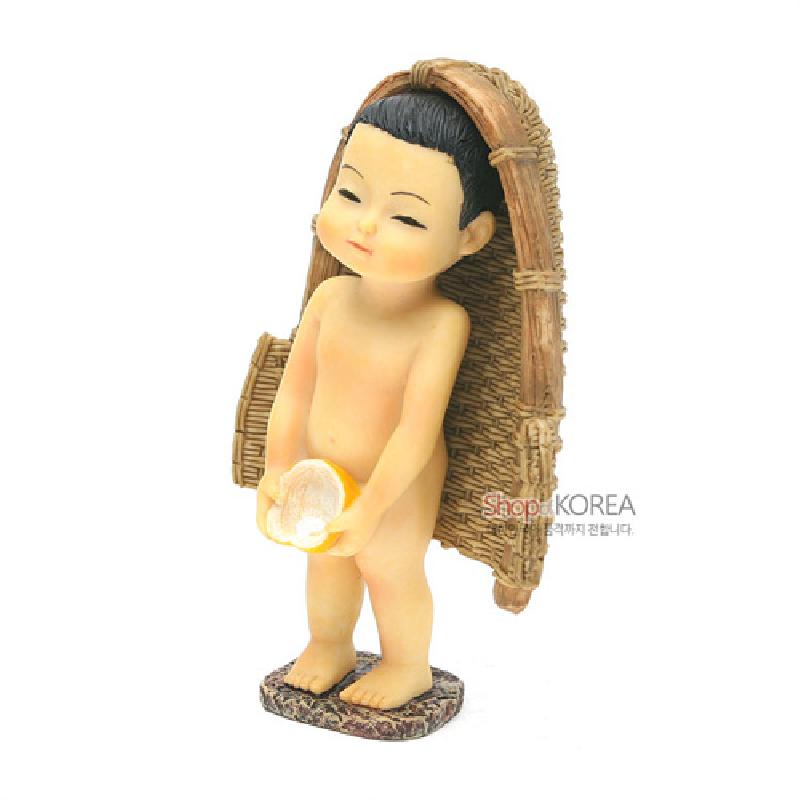레진 재질로 제작된 소년 조형과 등 뒤 짚 바구니, 대리석 질감 받침대가 조화된 전통풍 인형 장식.