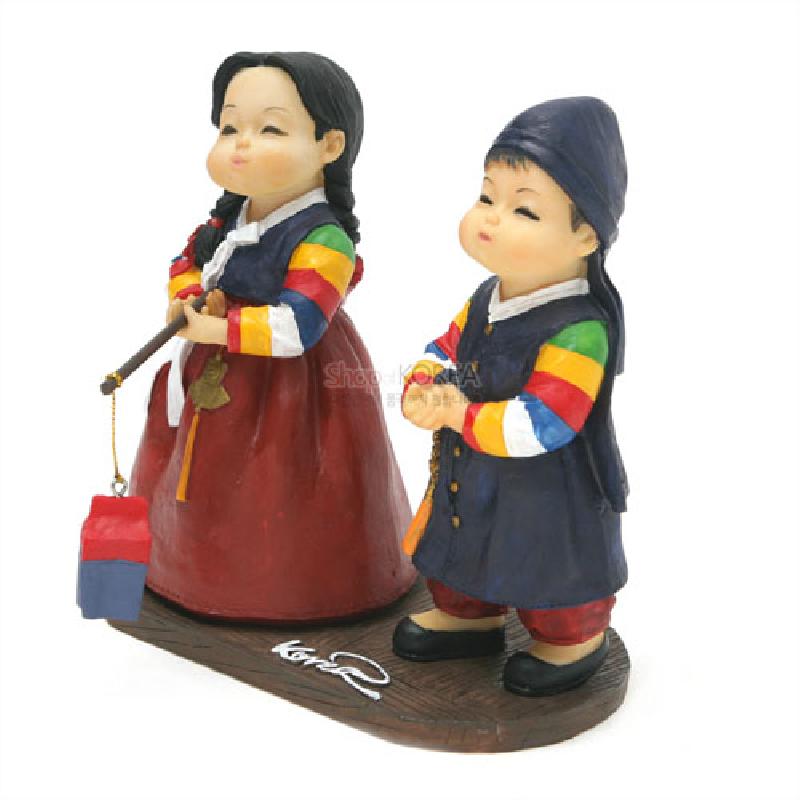 한복 차림 소년·소녀가 청사초롱을 든 형태의 수지 인형, 오방색 동정과 줄무늬 소매가 특징인 장식품.