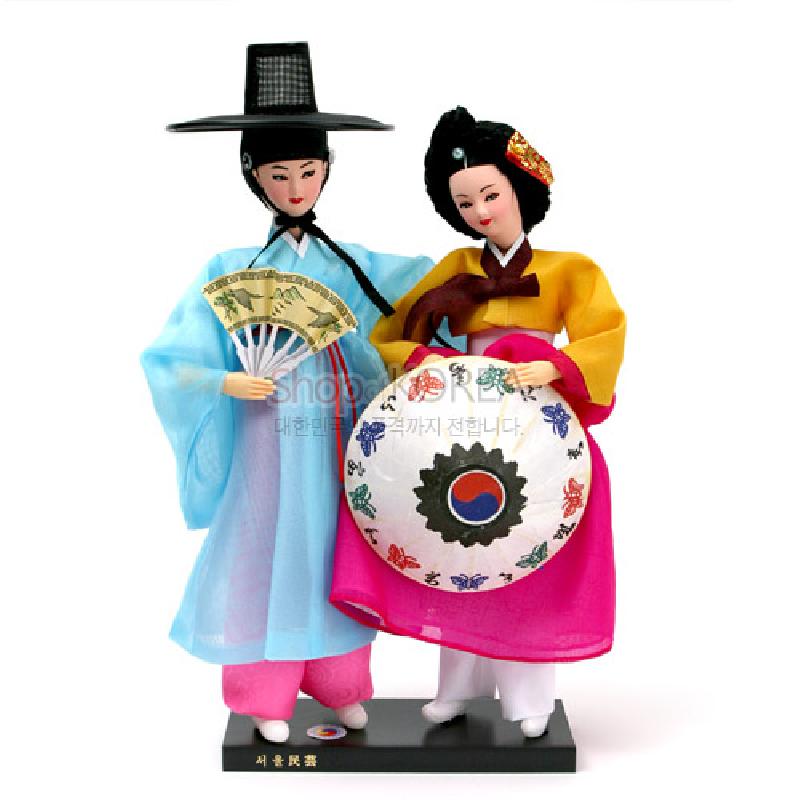 색동 저고리와 푸른 도포 한복, 태극 문양 부채와 나비 문양 장식이 어우러진 전통 한복 인형 세트.