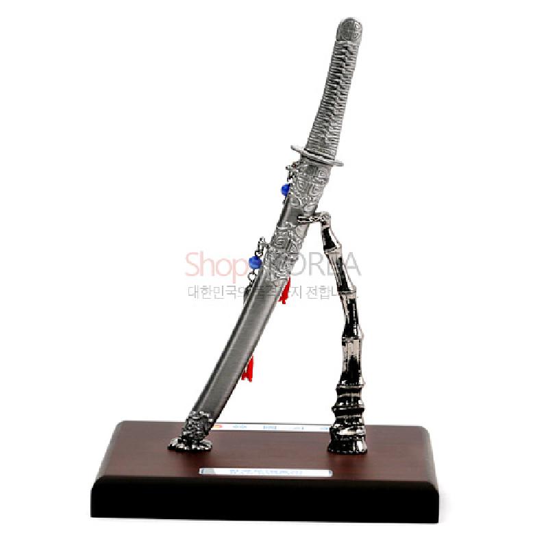 금속 재질의 한국도와 대나무 형상의 스탠드, 붉은·청색 장식 매듭이 더해진 금속 조형 장식품.