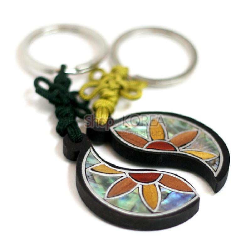흑단 바탕에 자개 상감으로 연꽃쌍 문양을 넣은 반달형 열쇠고리와 색실 매듭 장식.