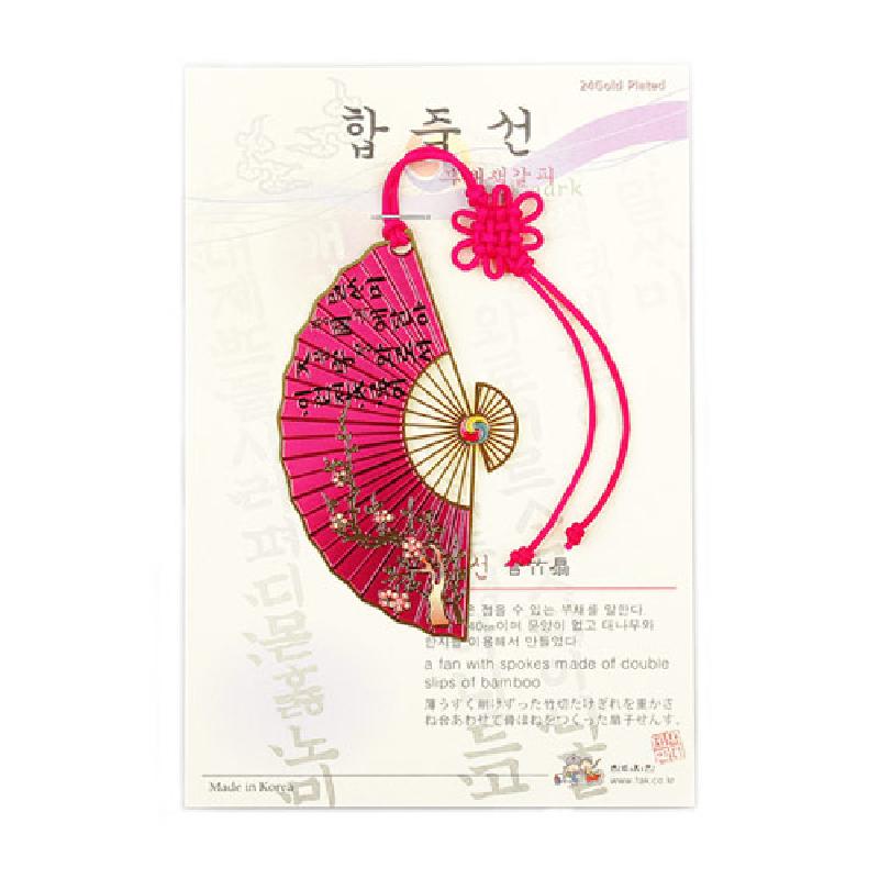 분홍색 금속 부채 모양에 금색 매화 문양과 훈민정음 글자 장식, 붉은 전통 매듭 끈이 달린 책갈피.
