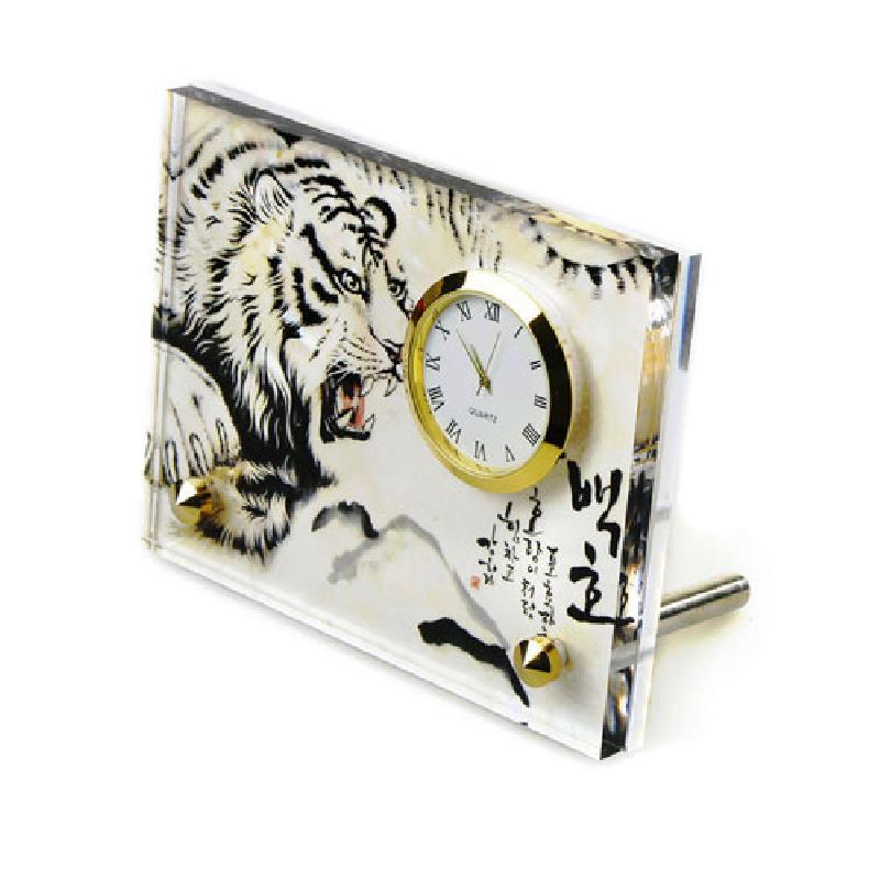 투명 아크릴 재질에 수묵 채색 기법으로 그린 백호 문양과 한글 서예가 어우러진 금테 원형 시계 장식.