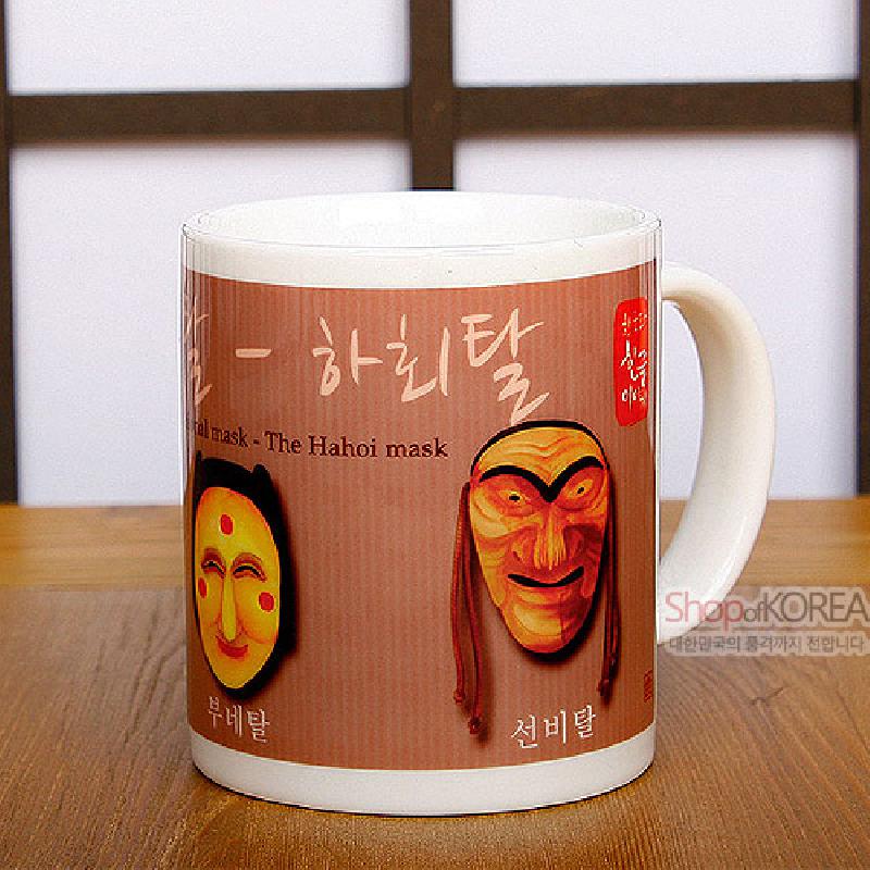 흰 도자 재질 머그컵에 갈색 바탕 색상과 하회 부네탈·선비탈 일러스트, 한글 캘리그래피가 인쇄된 디자인.