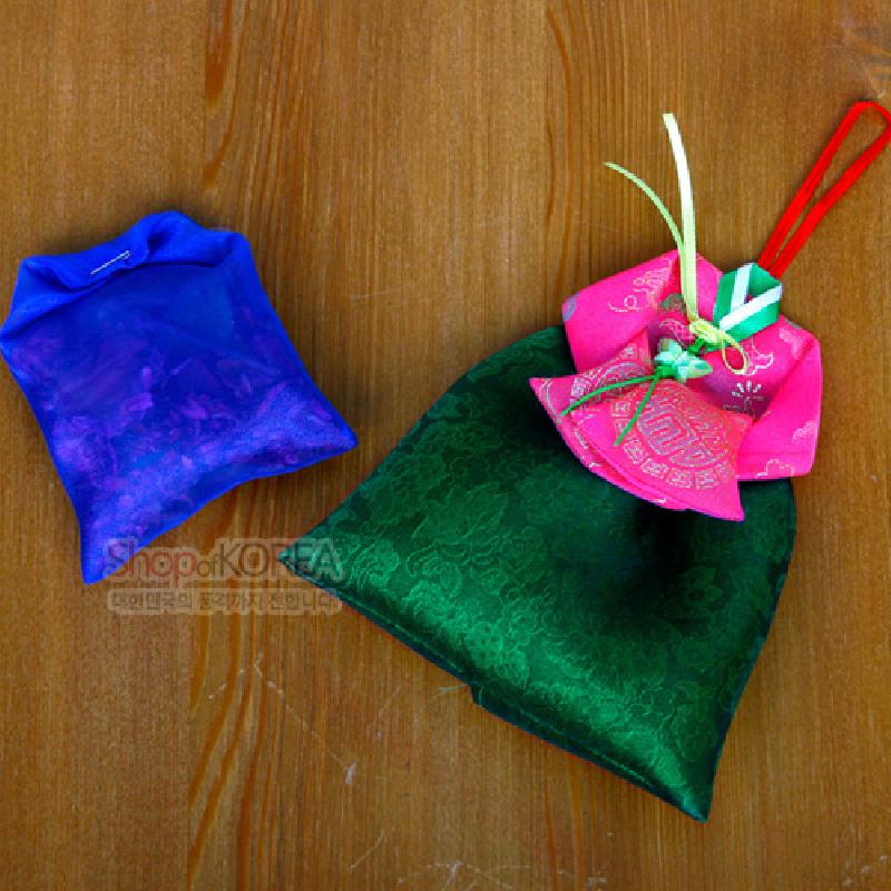 녹색 치마와 분홍 당의 형태의 비단 주머니, 전통 문양과 다채로운 매듭 장식이 특징인 향주머니.