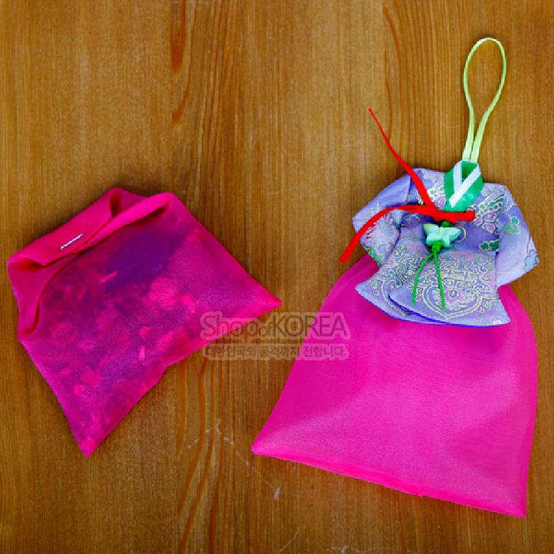 분홍 비단 소재의 치마 모양 주머니와 보라색 당의 문양 상단, 오색 끈과 매듭 장식이 어우러진 전통 향주머니.