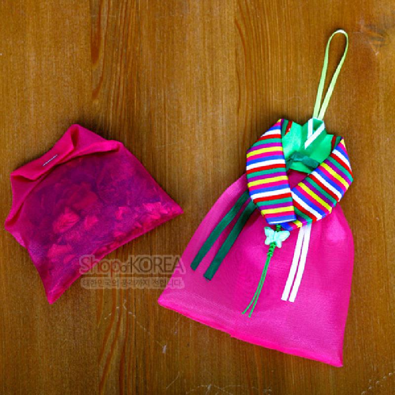 분홍색 비단으로 제작된 치마 모양 주머니와 색동 저고리 칼라 장식, 리본 매듭 장식이 어우러진 전통 벽걸이 향주머니.