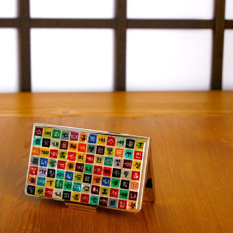 금속 재질 위에 다채로운 색상의 정사각형 칸에 훈민정음 자모를 배열한 디자인의 명함집.