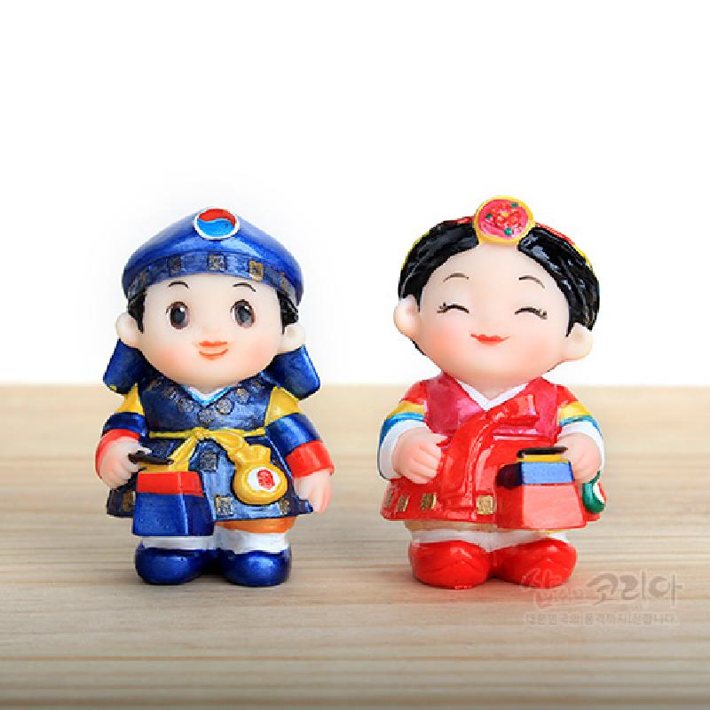 청색과 홍색 위주의 전통 복식을 입은 남녀 한복 인형 한 쌍, 채색 플라스틱 재질과 단청풍 색감, 청사초롱 소품이 특징인 장식 인형.