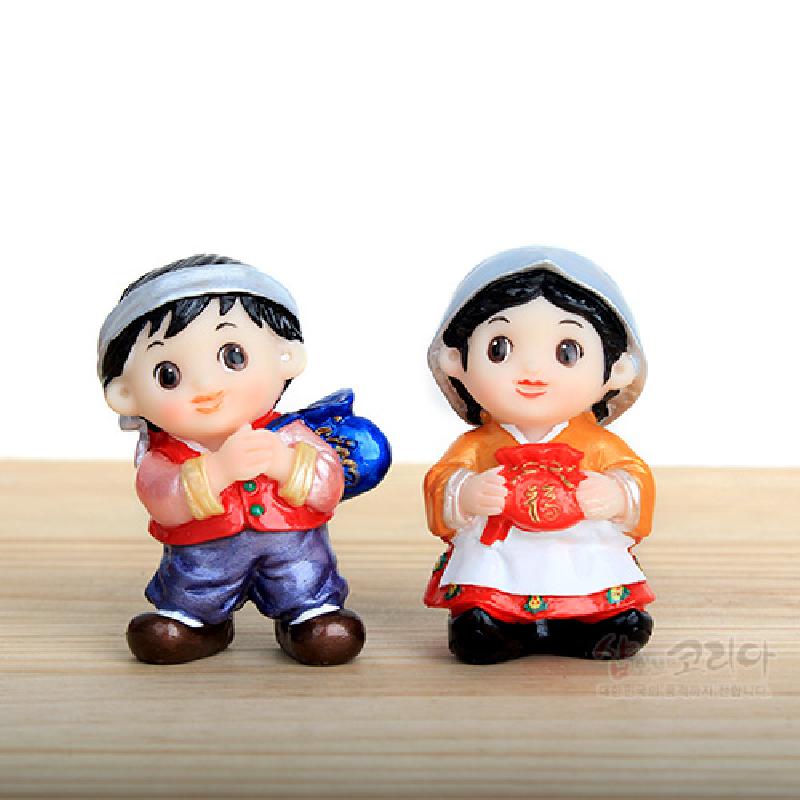 한복을 입은 남녀 아이가 청색·적색 복주머니를 든 형태의 소형 레진 민속인형 장식.