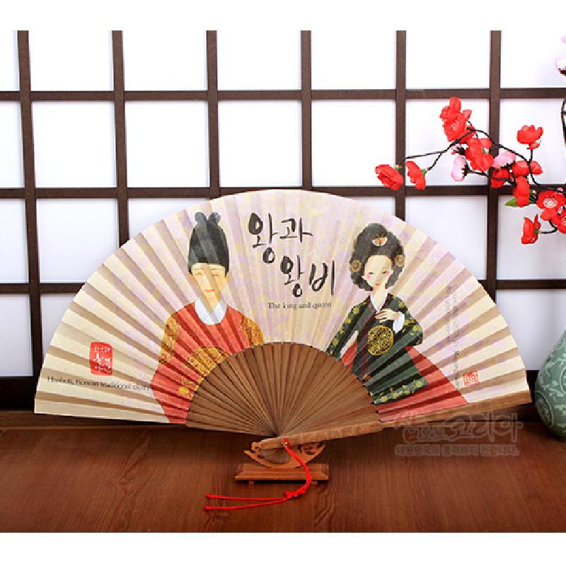 한지 재질에 수채화풍 왕과 왕비 삽화와 한글 서체가 인쇄된 접이식 부채, 갈색 목재 살대와 붉은 매듭 장식.