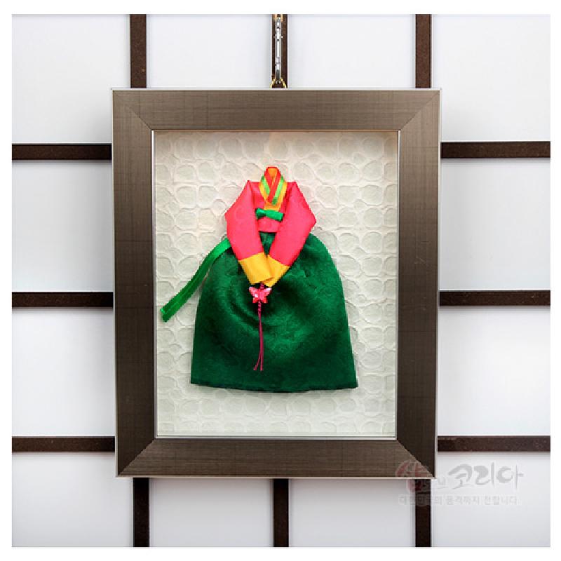 비단 재질의 녹색 치마와 분홍 저고리 한복 미니어처가 입체적으로 배치된 금속 테두리 전통 벽걸이 액자.
