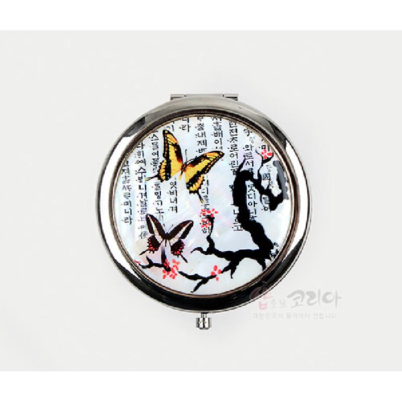 자개 바탕에 매화 가지와 나비 문양, 한글 서체가 어우러진 금속 원형 테두리 손거울.