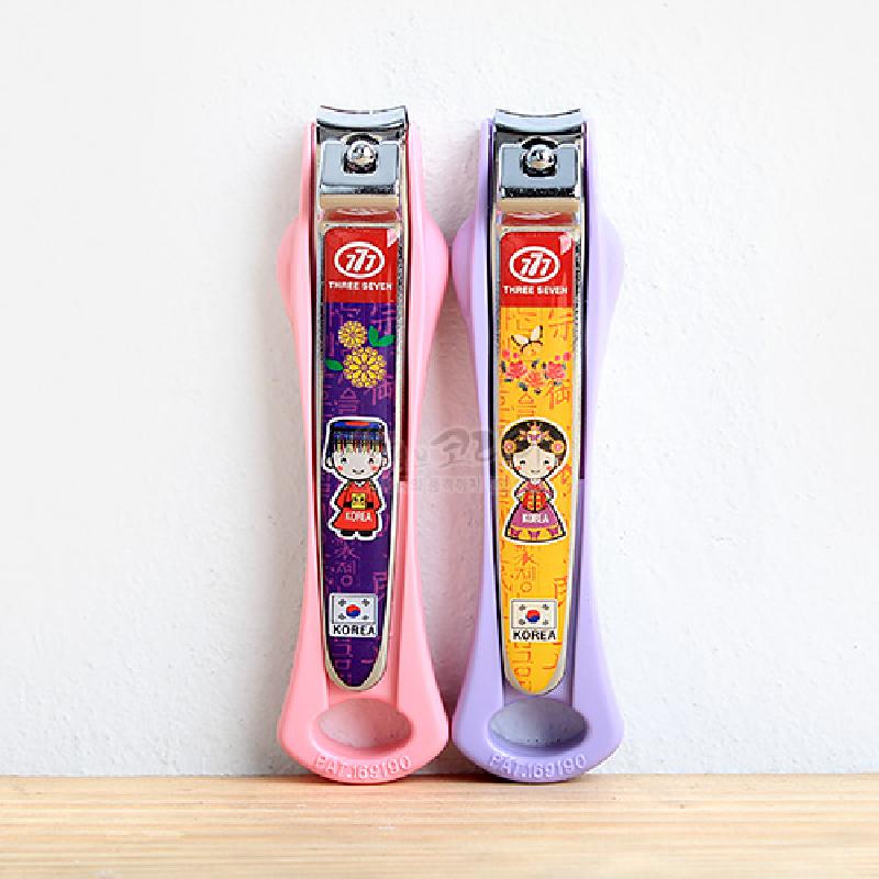 분홍·보라색 플라스틱 손잡이 위 금속 손톱깎이에 예복 입은 왕과 왕비 캐릭터, 화려한 꽃과 문자 문양이 인쇄된 디자인.