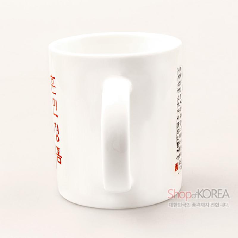 백색 도자 재질에 붉은색과 검은색 훈민정음 언해 서체가 인쇄된 직선형 머그컵.