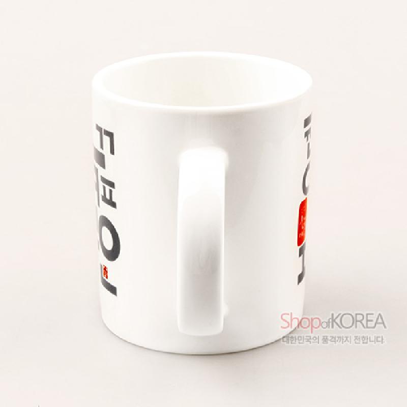 백색 도자 재질에 검정 한글 타이포그래피와 붉은 인장 문양이 배치된 머그컵.