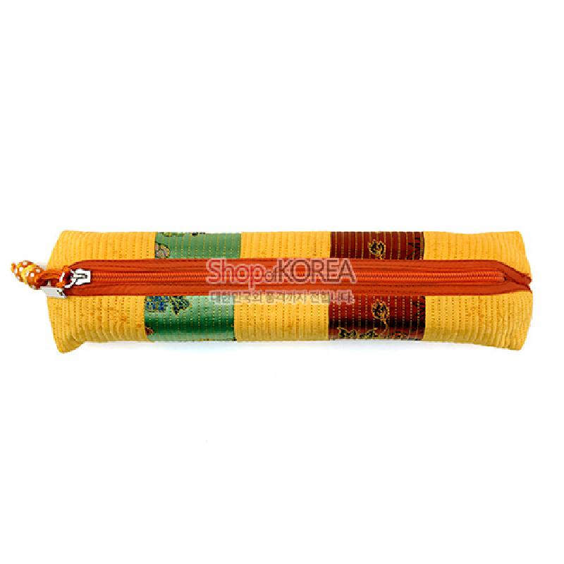 누비 기법으로 제작된 황색 바탕의 직사각형 필통, 녹색·갈색 패치와 꽃문양 직물 장식, 주황색 지퍼 여밈 디자인.