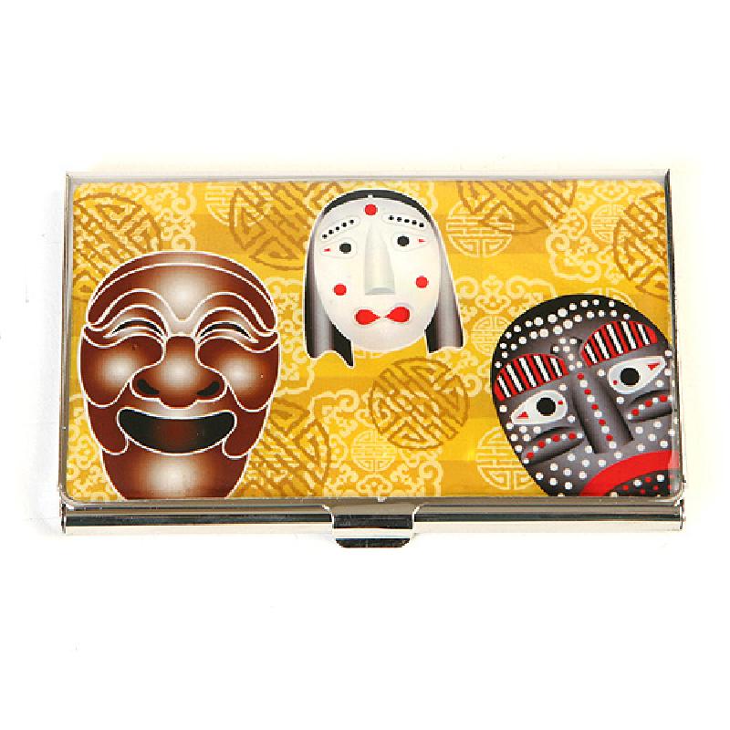 금속 재질 위에 노란색 전통 문양 배경과 한국 전통 탈 세 얼굴이 컬러로 인쇄된 명함집. 금속 재질 위에 노란색 전통 문양 배경과 한국 전통 탈 세 얼굴이 컬러로 인쇄된 명함집.