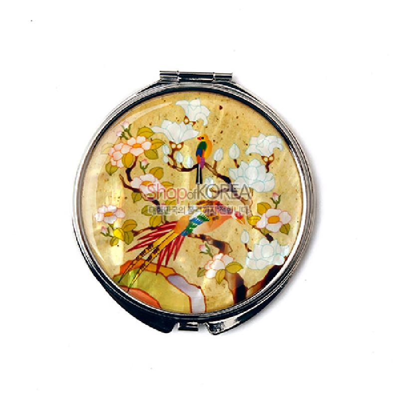 자개 상감 기법으로 화조도 문양을 표현한 원형 금속 손거울, 노란 바탕에 다채로운 채색이 돋보이는 디자인.