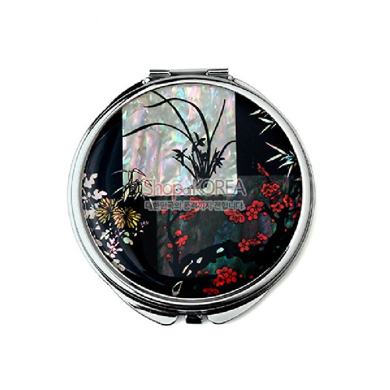 자개 상감 기법으로 사군자 문양을 표현한 금속 테두리 원형 손거울, 검은 바탕에 붉은 꽃과 대나무, 난초 색채 대비가 돋보이는 디자인.