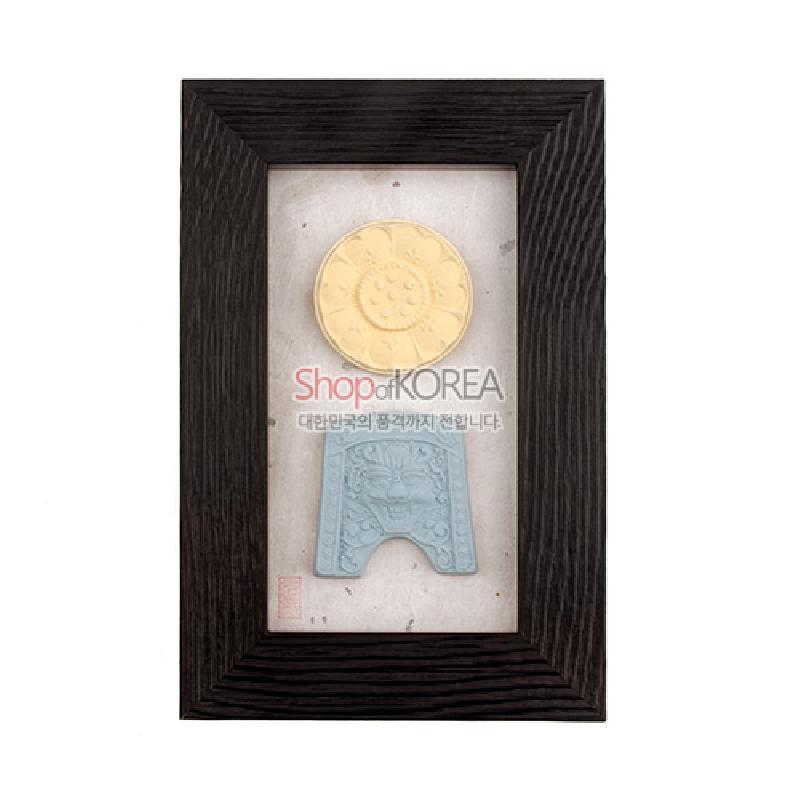 노란색 연꽃무늬와 하늘색 귀면문이 양각으로 새겨진 향 장식을 담은 흰 바탕과 짙은 나무 액자 구성.